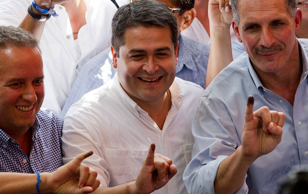 National Party presidential candidate Juan Orlando Hernandez, center, Tegucigalpa mayoral candidate Nasry Tito Asfura, right, and congressional candidate Ricardo Alvarez hold up their ink-stained pinkies after voting at a polling station in Tegucigalpa, Honduras.