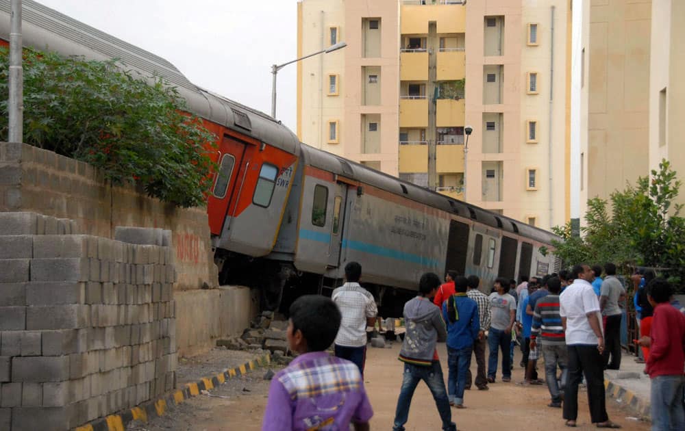 People watch as Rajdhani Express coaches derailed and fall on the near by road during backing up at city railway station in Bengaluru.