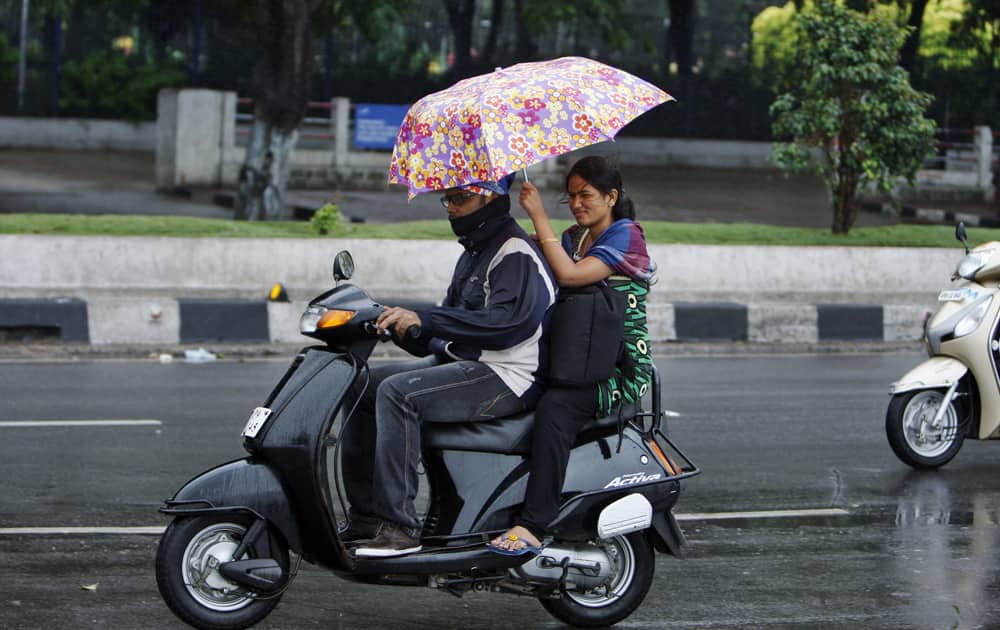 A woman shields her relative on a two-wheeler from rain in Hyderabad. Meteorological Department said Cyclone hit Andhra Pradesh state with winds of 80 to 90 kph (50 to 55 mph) and heavy rains.