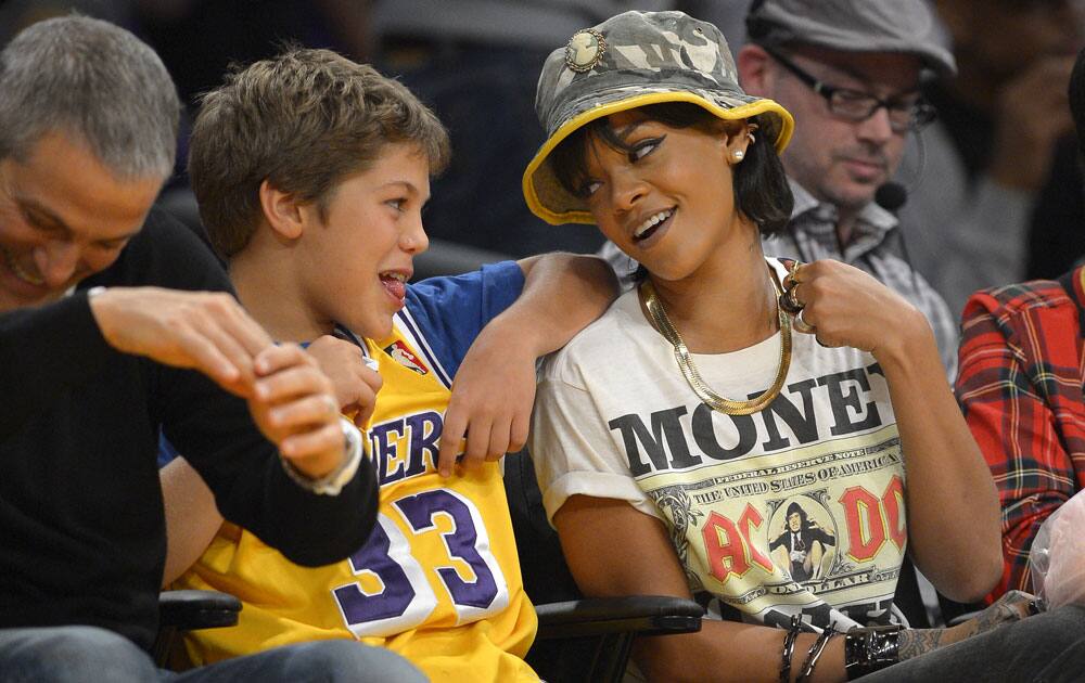 Singer Rihanna, right, talks with talent agent Ari Emanuel, left, and his son as they watch the Los Angeles Lakers play the Golden State Warriors during the second half of an NBA basketball game.