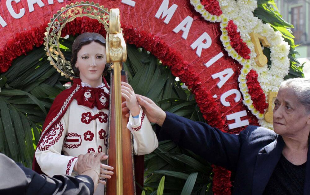 Women touch a statue of Saint Cecilia, the Patron Saint of music, in Garibaldi square in Mexico City.