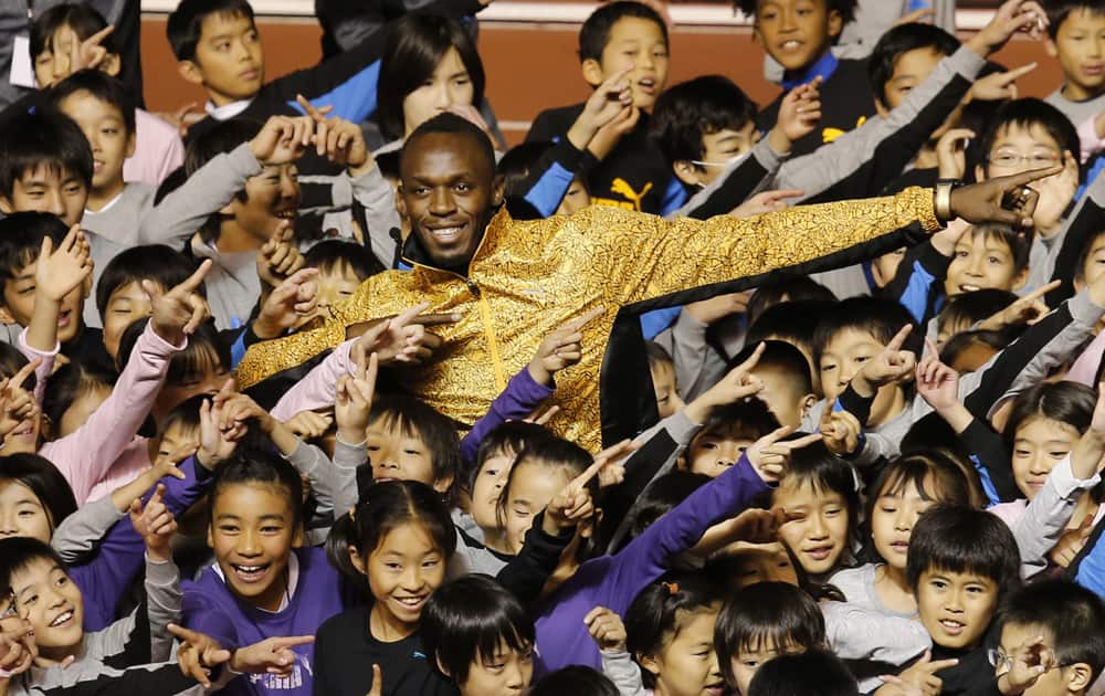 Olympic gold medalist Usain Bolt of Jamaica poses with children during an athletic clinic at the national stadium in Tokyo, Japan.