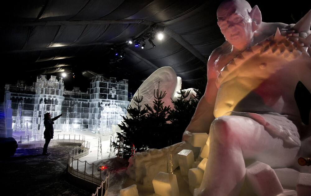 A woman poses for photographers beside ice sculptures in the