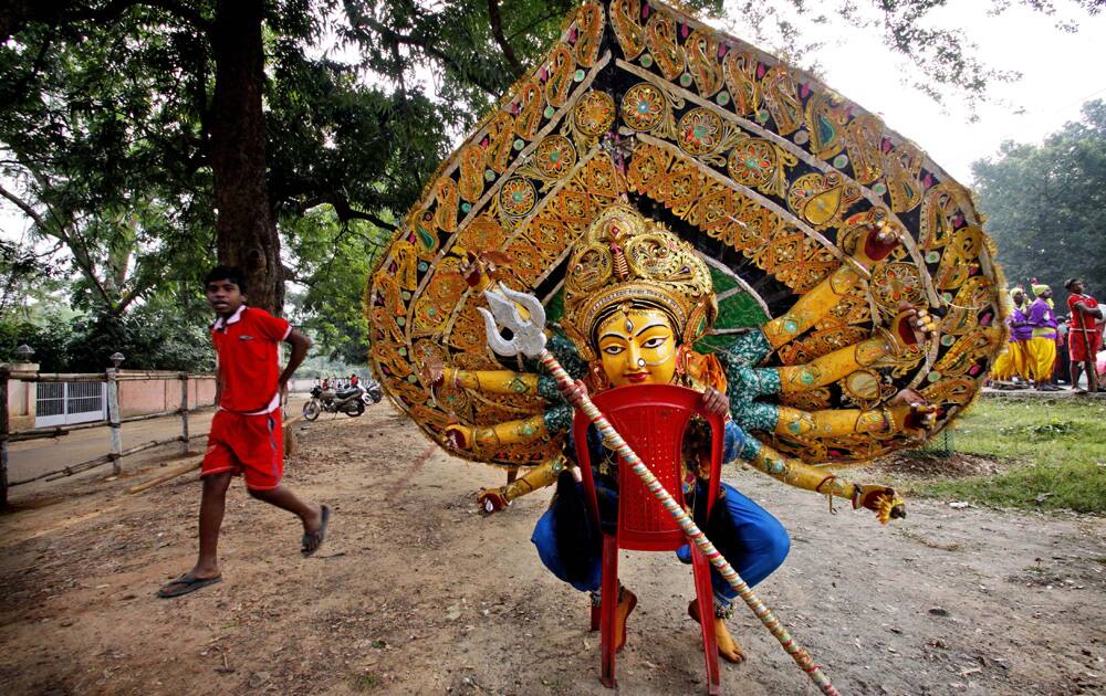 A folk artist wearing the mask of Goddess Durga rests after a dance performance in Bhubaneswar.