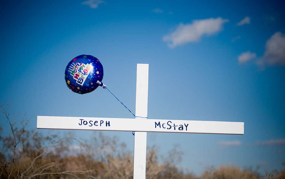 A birthday balloon blows in the wind after it was placed on a memorial cross for Joseph McStay, whose body, along with his wife and two children were found in a shallow grave, in Victorville, Calif.