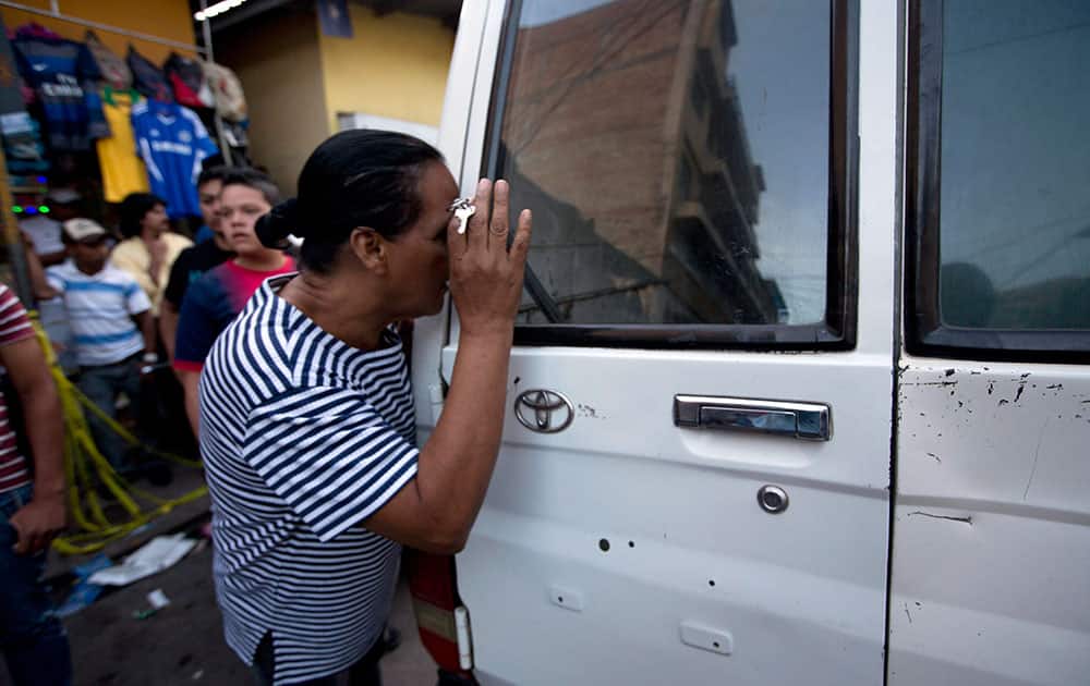 A woman tries to see the body of a taxi driver who was killed in downtown Tegucigalpa, Honduras.