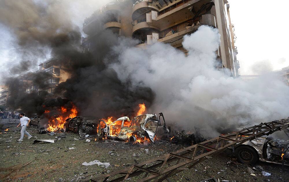 A Lebanese man runs in front of burned cars, at the scene after two explosions have struck near the Iranian Embassy killing many, in Beirut, Lebanon.
