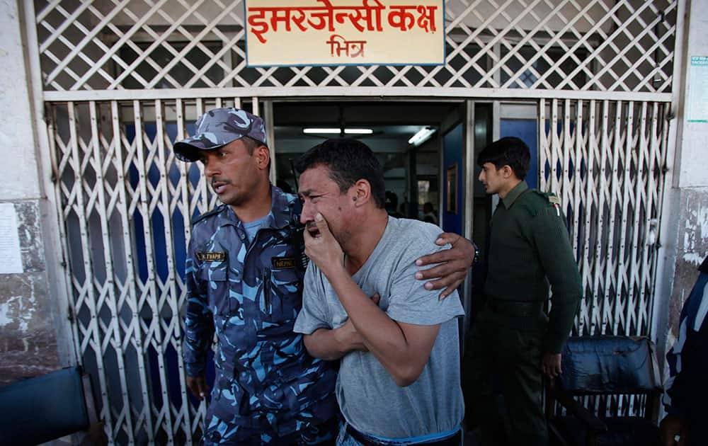 A Nepalese security officer consoles the father of an inured child outside the Bir Hospital where children wounded in an explosion are being treated in Katmandu, Nepal.