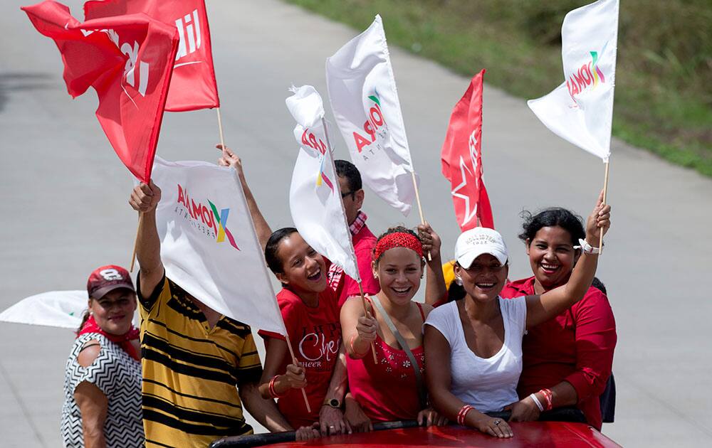 Supporters of presidential candidate Xiomara Castro hold up flags and cheer as they ride on a truck to go towards their candidate`s closing campaign rally in Juticalpa, Honduras.