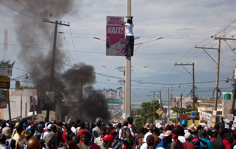 A demonstrator removes a poster of Haiti`s President Michel Martelly during a protest against Martelly on the anniversary of the Vertières battle in Port-au-Prince, Haiti.