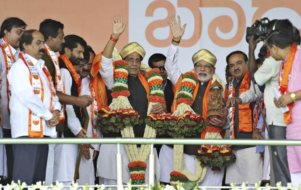 Bharatiya Janata Party prime ministerial candidate Narendra Modi and party president Rajnath Singh, wave to their supporters after their felicitation at a public rally in Bangalore.