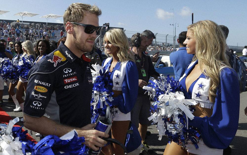 Red Bull driver Sebastian Vettel of Germany walks past the Dallas Cowboy cheerleaders before the Formula One US Grand Prix auto race at the Circuit of the Americas.