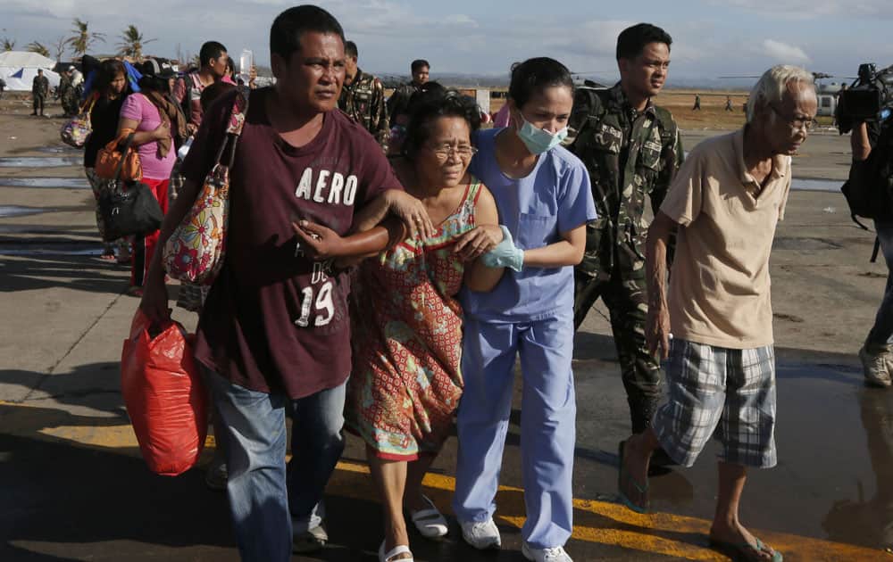 A patient is assisted by a nurse and family to an evacuation flight at the airport Saturday, Nov. 16, in Taclaban, Leyte province, central Philippines.