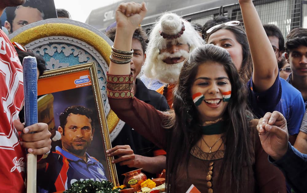 Fans of Sachin Tendulkar celebrate in front of his portrait as they wait in queue to watch Tendulkar’s last test match in Mumbai.