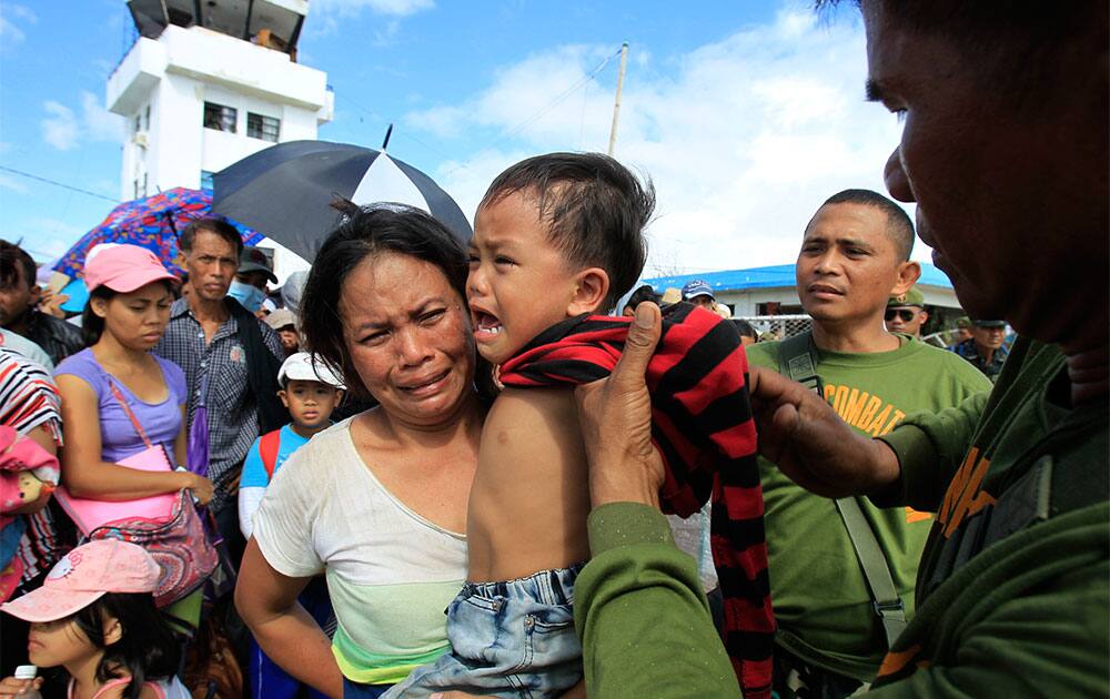 A woman and her child are pulled out of the frantic crowd to be prioritized on an evacuation flight in Tacloban, central Philippines.
