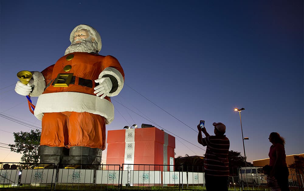 A man takes a picture of a giant Santa Claus statue that is on display in the Center Norte mall parking lot, marking the start of the Christmas season in Sao Paulo, Brazil.