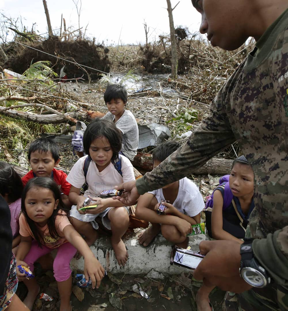 Children, who say they fled when armed men were seen in their village, are given biscuits and chocolates by a police officer while waiting in Tacloban city, Leyte province in central Philippines.
