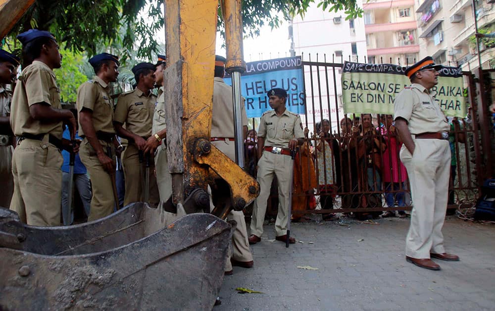 Policemen stand near an earthmover as residents of Mumbai`s Campa Cola housing colony block the entrance to their colony in Mumbai.