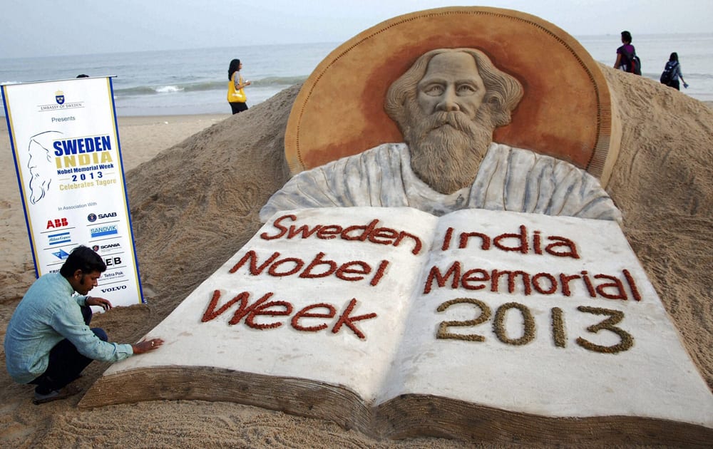 Sand artist Sudarshan Patnaik creates a sand sculpture of Rabindranath Tagore in Puri on Tuesday to mark the centenary of his Nobel Prize in Literature, on the occasion of `Sweden India Nobel Memorial Week 2013`.