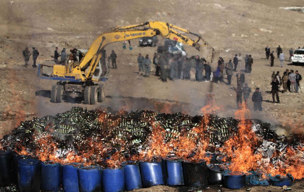 Afghan security officials look at alcohol cans and opium set on fire a drug burning ceremony on the outskirts of Kabul.