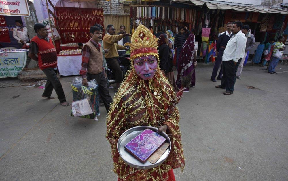 An Indian girl stands dressed as a Hindu deity seeking alms during the annual cattle fair in Pushkar, in the western state of Rajasthan.