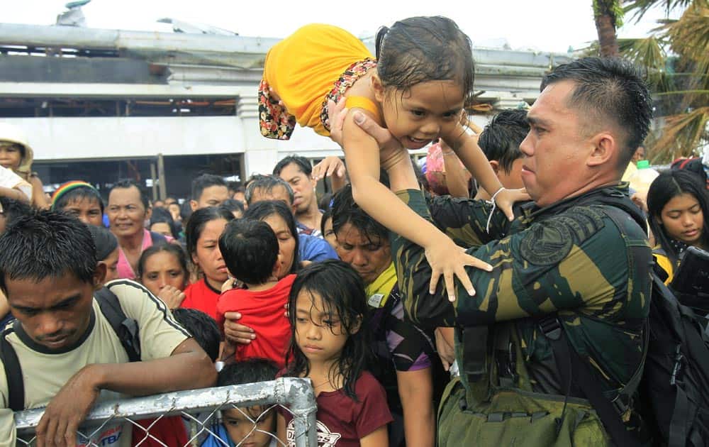Philippine military personnel try to prioritize children and women first as people wait for evacuation flights in Tacloban, central Philippines.