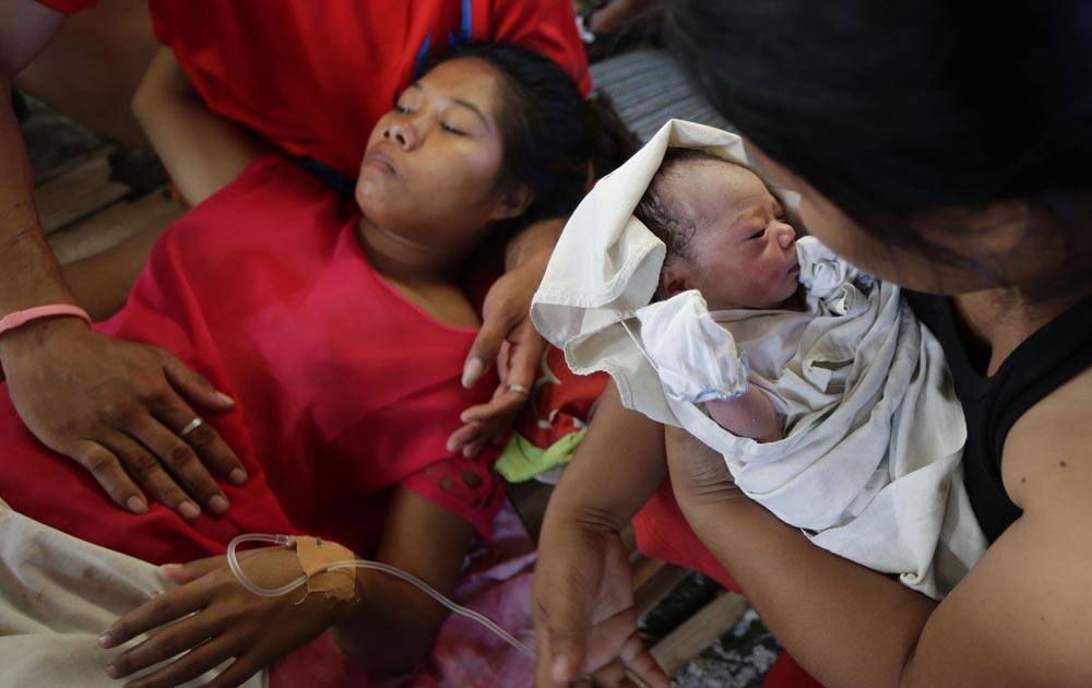 New-born baby Bea Joy is held as mother Emily Ortega, 21, rests after giving birth at an improvised clinic at Tacloban airport.