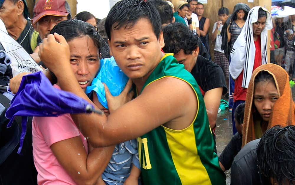 A husband and wife protect their baby from the rain as they wait for an evacuation flight in Tacloban, central Philippines.