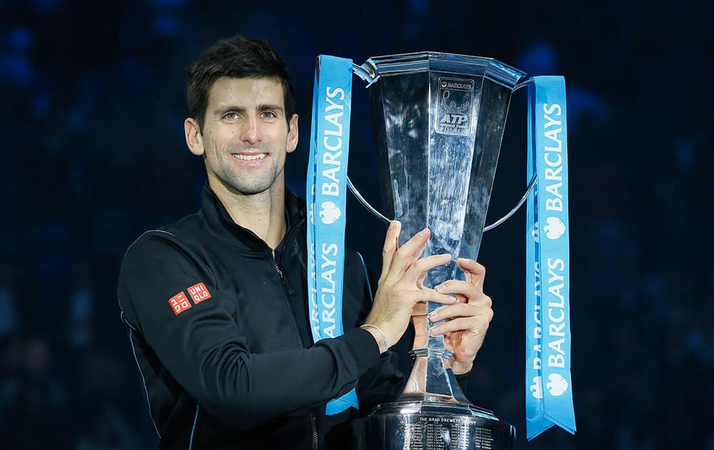 Novak Djokovic of Serbia holds up the ATP World Tour Finals tennis trophy as he poses for photographers after defeating Rafael Nadal of Spain at the O2 Arena in London.
