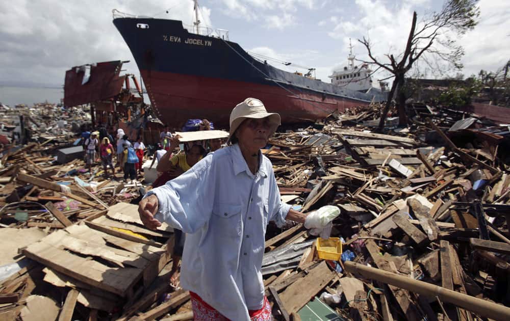 Survivors walk through the rubble of damaged homes and a ship that was washed ashore in Tacloban city, Leyte province, central Philippines.