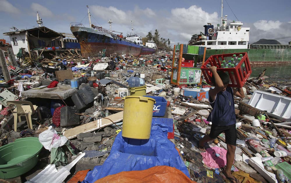 A Filipino boy carries bottled water amongst the damaged houses where a ship was washed ashore in Tacloban city, Leyte province, central Philippines.