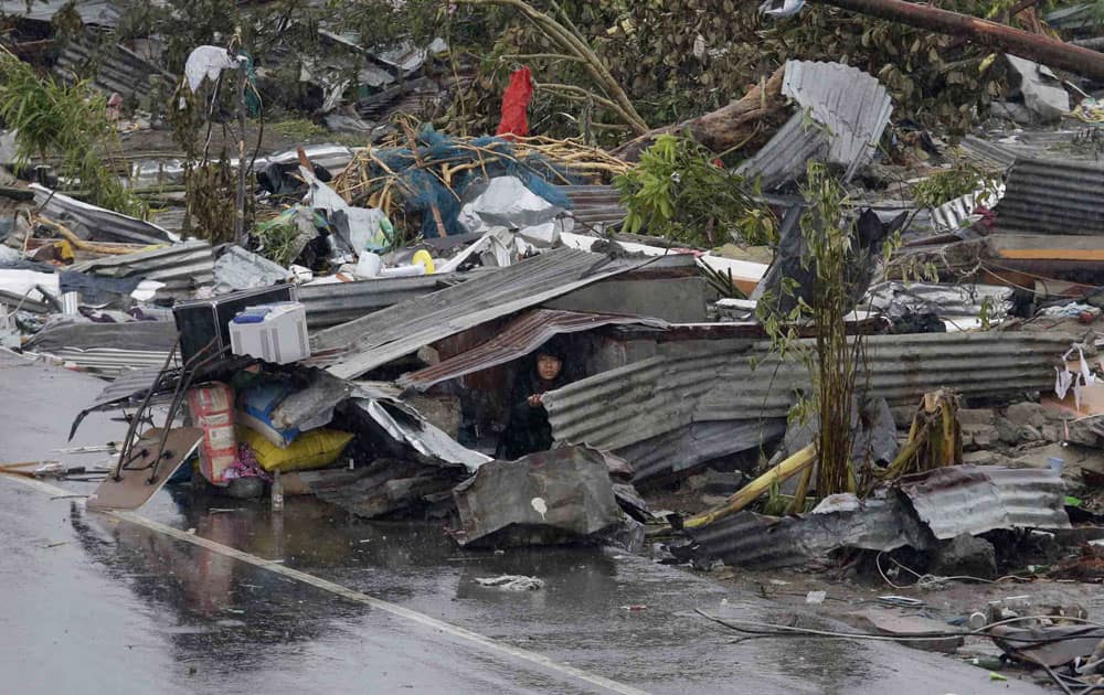 A woman looks out from the remains of her damaged house in Tacloban city, Leyte province, central Philippines.