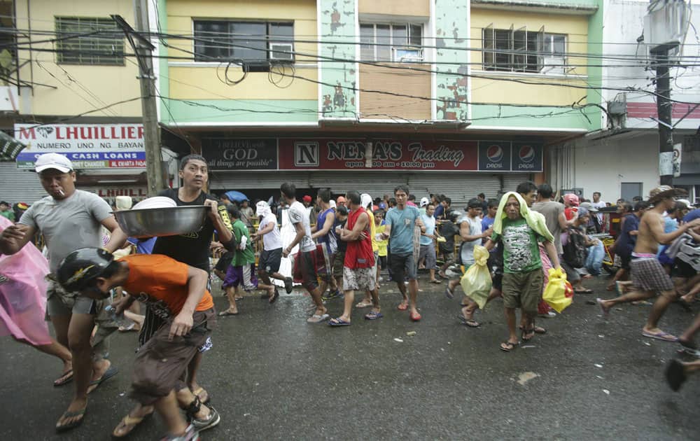 Residents run out carrying food after storming a grocery shop in Tacloban city, Leyte province central Philippines.