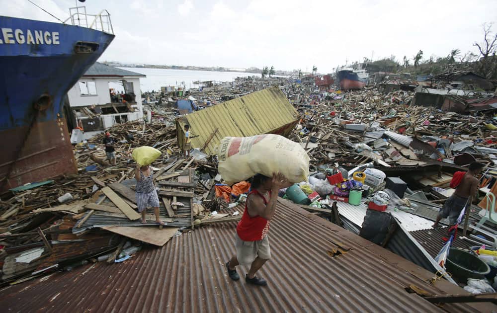 Residents carry relief goods on top of destroyed homes after strong waves caused by Typhoon Haiyan slammed into Tacloban city, Leyte province central Philippines.