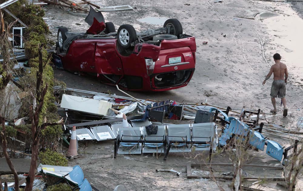 A resident passes by toppled car outside an airport terminal after powerful Typhoon Haiyan slammed into Tacloban city, Leyte province central Philippines.