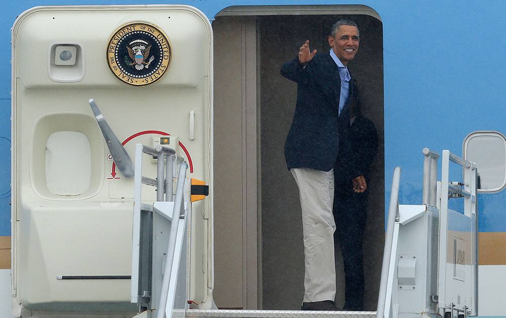 President Barack Obama turns and waves as he boards Air Force One during a rainstorm prior to his departure from Miami International Airport.
