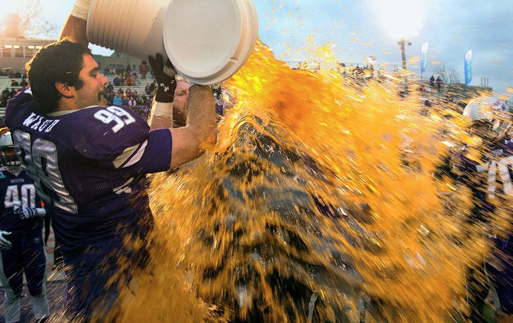 Western`s Daryl Waud (99) and Matt Van Praet give head coach Greg Marshall a dousing after defeating Queens University in the Yates Cup championship college football game in London, Onario.