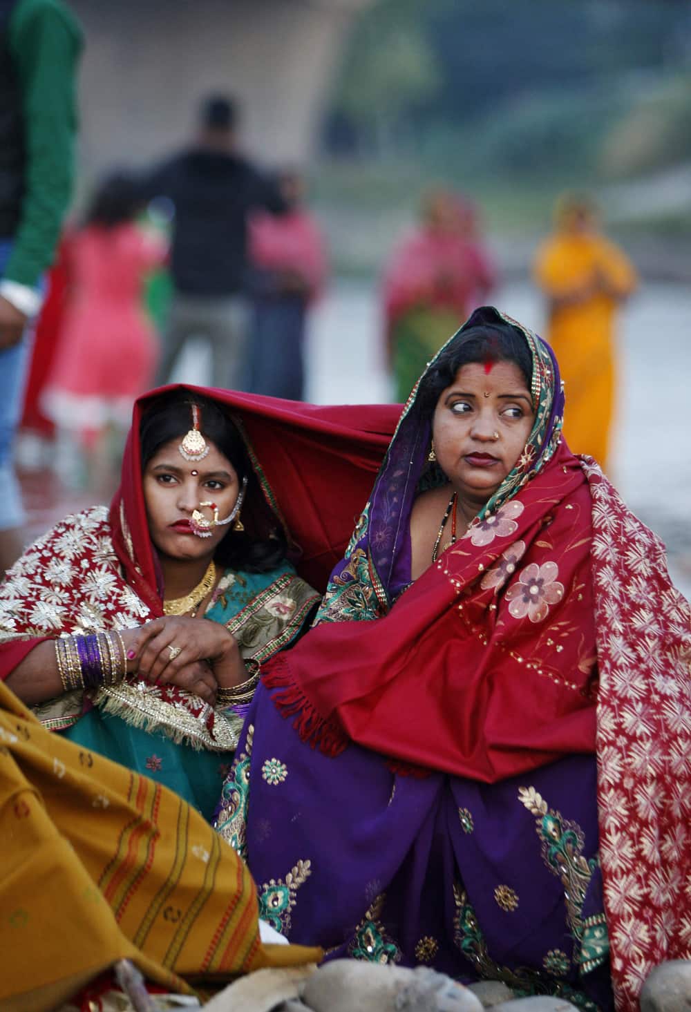 Hindu devotees share a shawl as they rest before performing rituals at River Tawi during Chhath festival in Jammu.