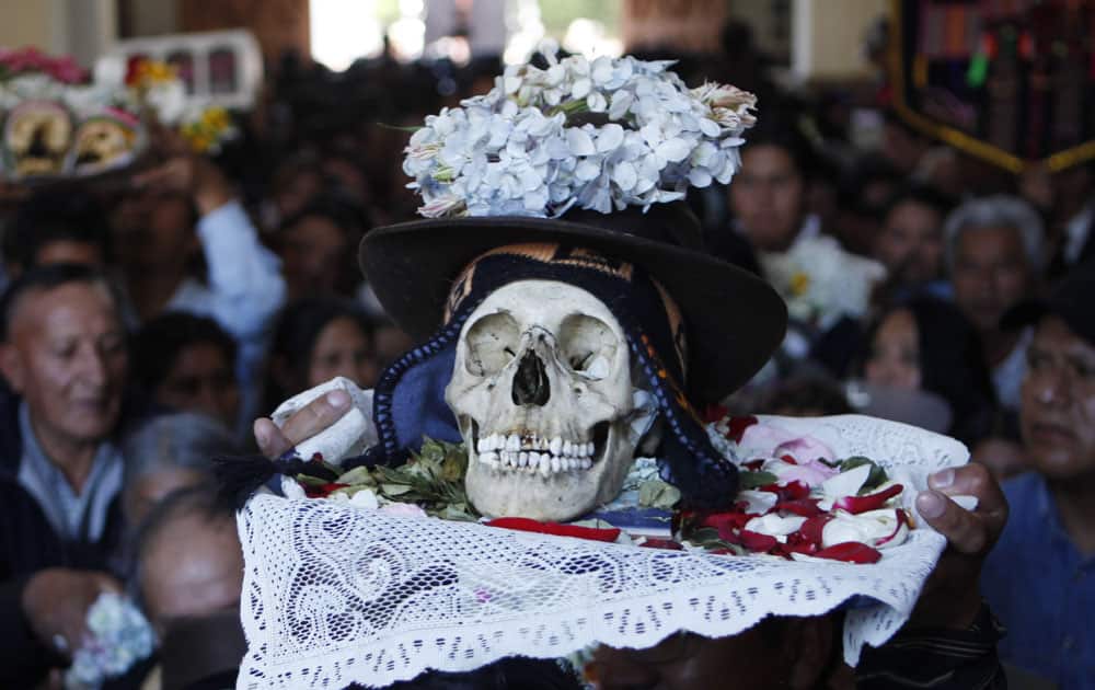 A man carries a decorated human skull or
