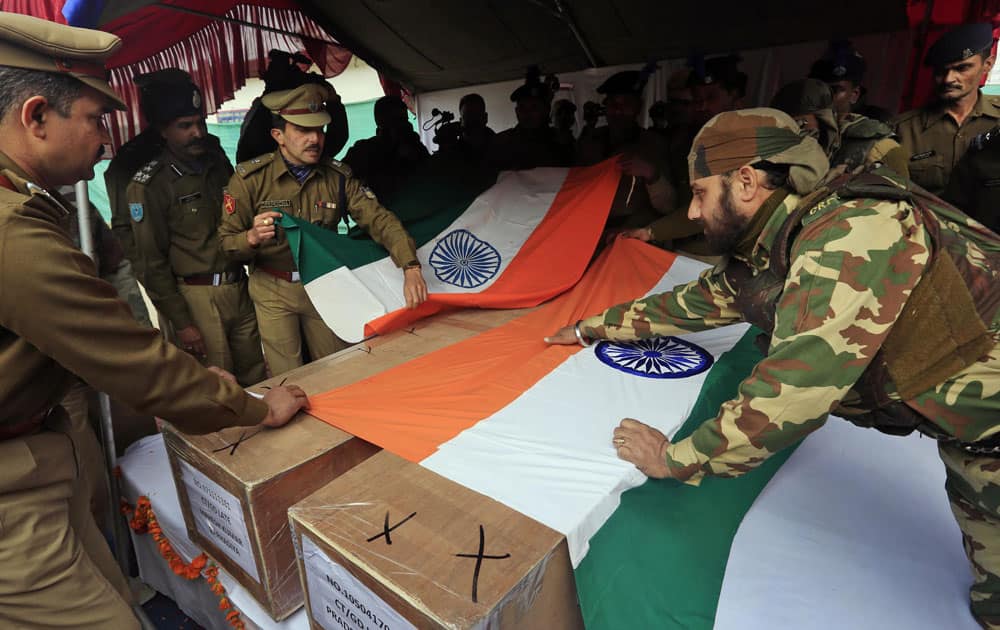 Indian paramilitary officers cover the coffin of their colleagues with Indian flags during a wreath laying ceremony inside their base camp on the outskirts of Srinagar.