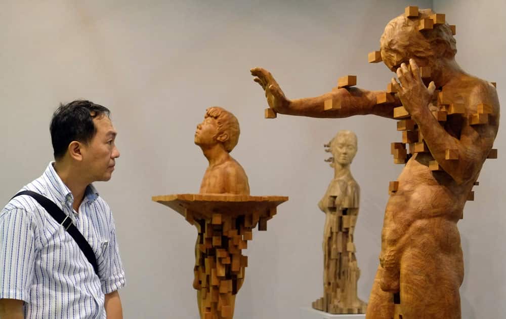 A visitor looks at a wood carving by Taiwanese artist Donald Harn entitled