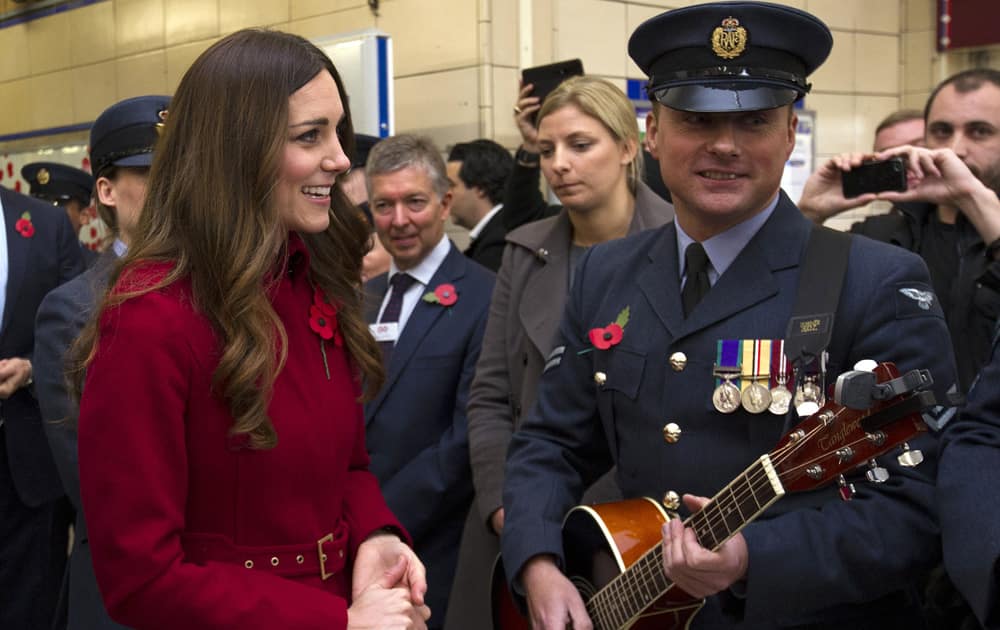 Kate, the Duchess of Cambridge, reacts with an unidentified member of the Royal British Legion, at Kensington High Street Station, in London.