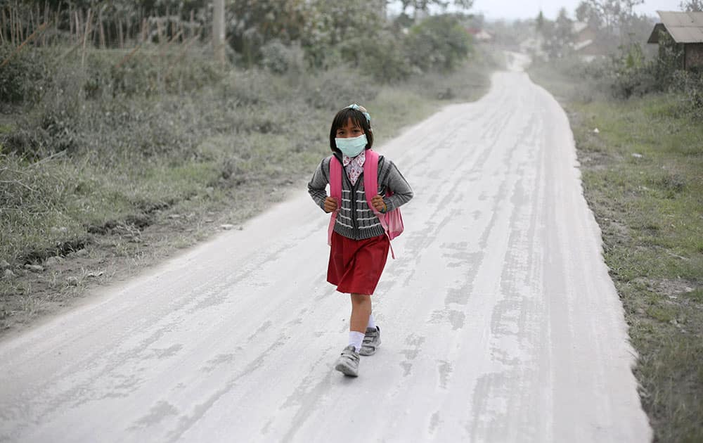 A student walks on a road covered with volcanic ash from the eruption of Mount Sinabung in Tiga Nderket, North Sumatra, Indonesia.