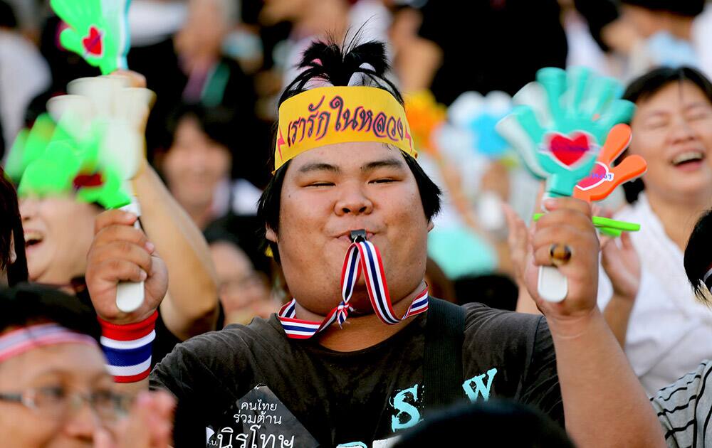 A Thai demonstrator waves clapping tools and blows a whistle during an anti-amnesty bill demonstration at the Democracy Monument in Bangkok, Thailand.