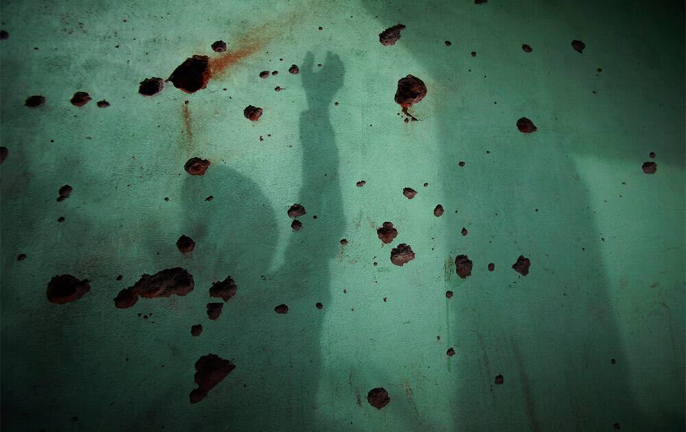 Shadows are reflected on the wall as Indian villager Ram Lal, 60, who was injured in the Oct.24 firing by Pakistani troops shows shell marks on the wall of his house at Garkhal village near the India Pakistan border, about 35 kilometers (22 miles) from Jammu, India.