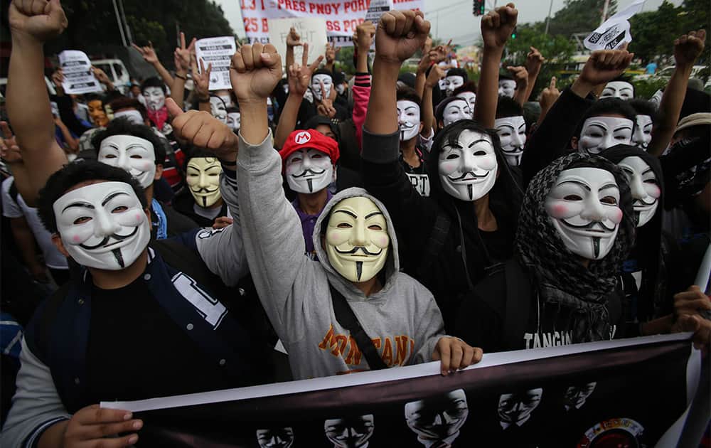 Filipino student protesters wearing masks raise their clenched fist as they pass by the gates of the House of Representatives in suburban Quezon city, north of Manila, Philippines.