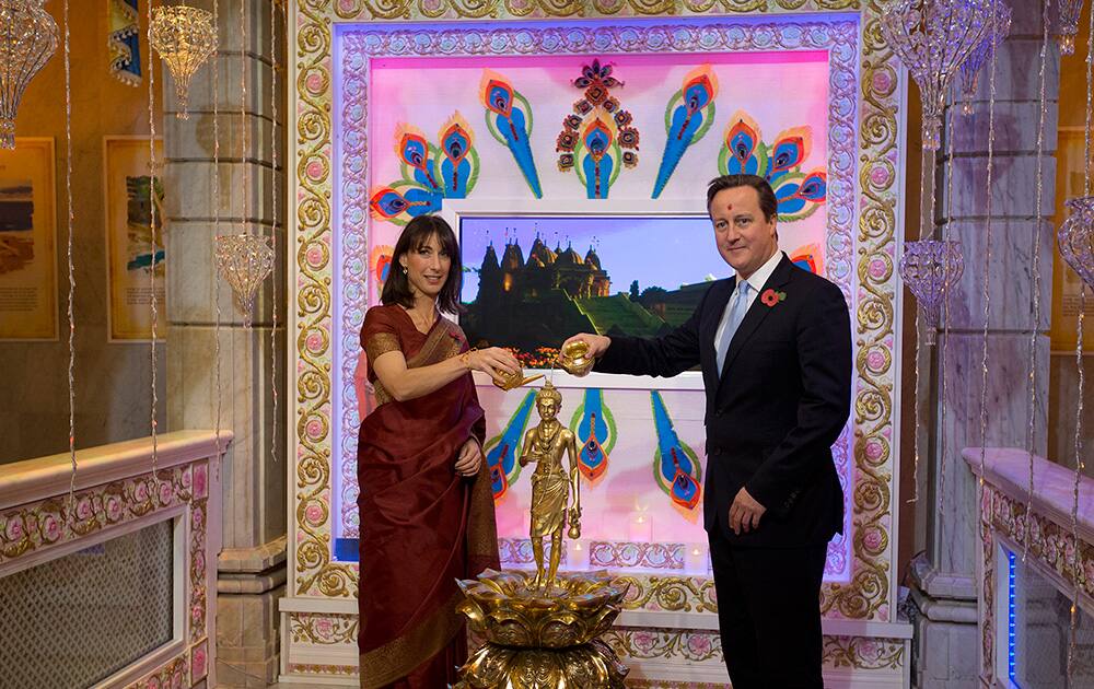 Britain`s Prime Minister David Cameron and his wife Samantha pour water on a Hindu deity as they arrive for a visit to the Hindu temple the Shri Swaminarayan Mandir in London, during Diwali.
