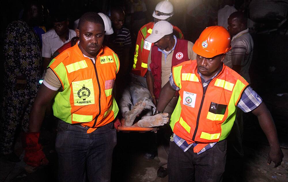 Rescue workers carry a survivor from the rubble of a building under construction which collapsed in Lagos, Nigeria. Emergency officials said casualty figures from the incident were unclear as they continued their search for survivors.