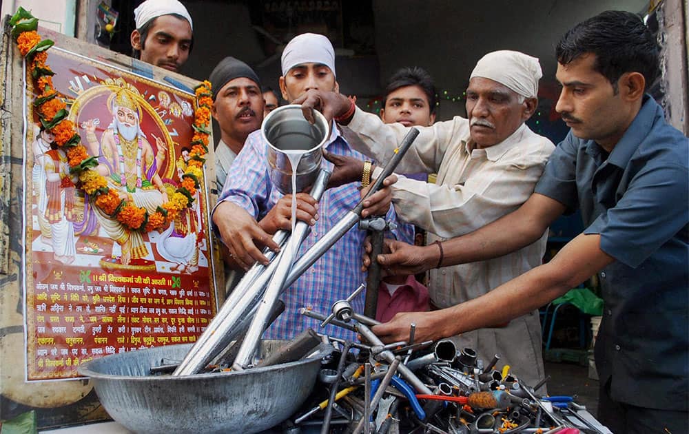 Artisans cleaning their tools with milk and performing puja on the occasion of Vishwakarma Day in Amritsar.
