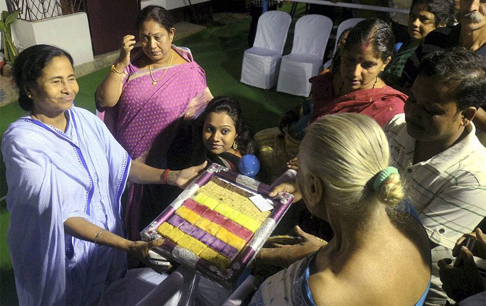 West Bengal Chief Minister Mamata Banerjee distributes sweets to her guests before offer prayer to Goddess Kali Idols in Kolkata on Saturday night on the occassion of Kali Puja.
